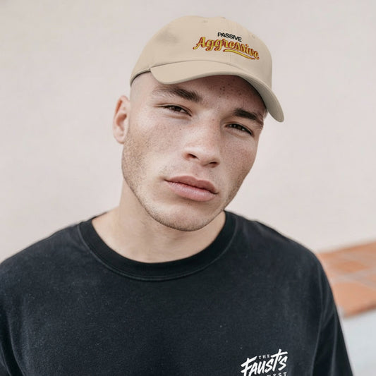 Man wearing a beige cap with text and a black shirt with text, against a neutral background