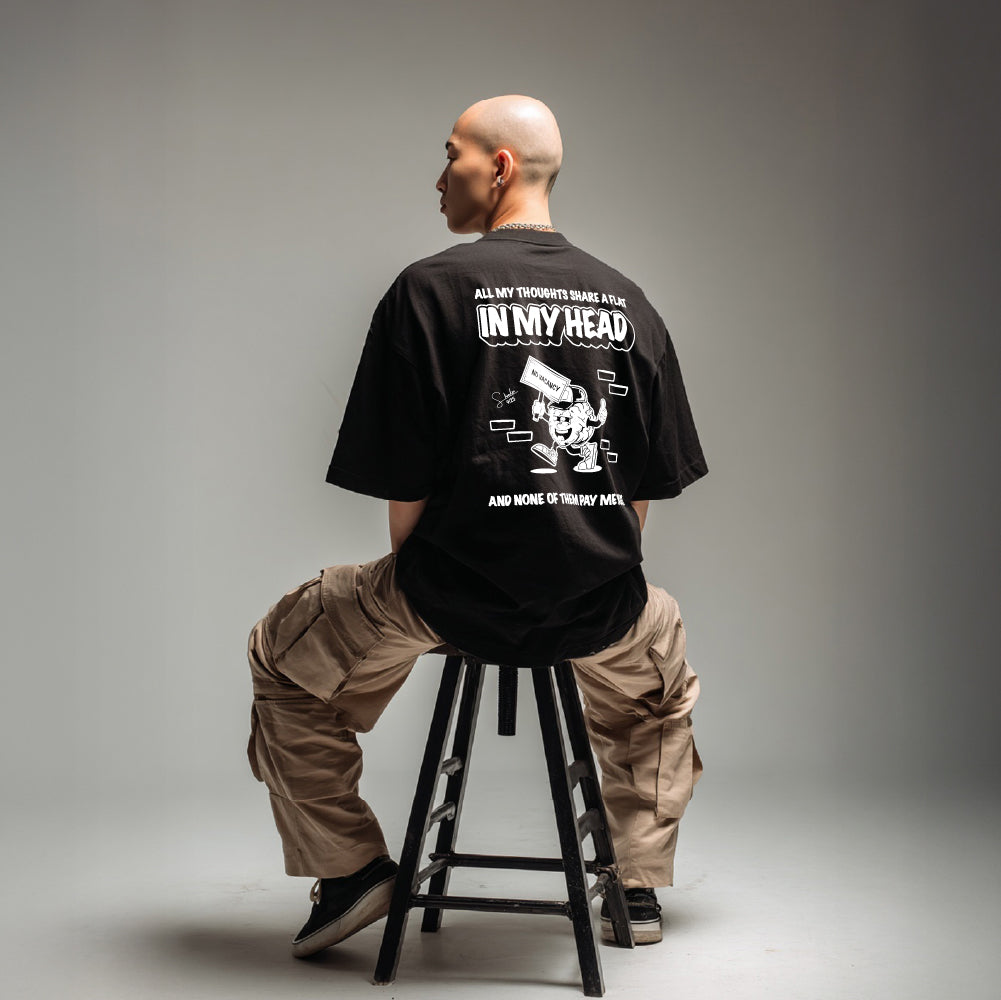 Person sitting on a stool wearing a black t-shirt with text and graphics.