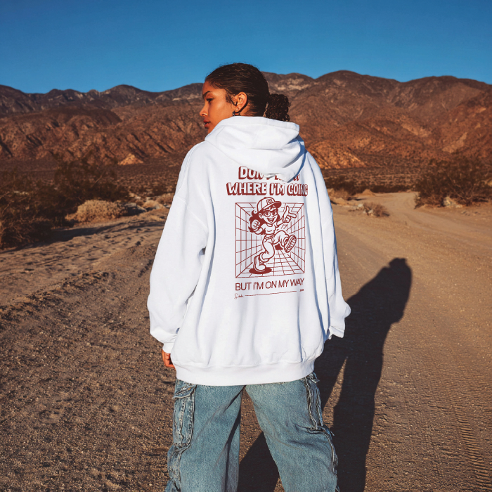 Person wearing a white hoodie with a graphic design in a desert landscape