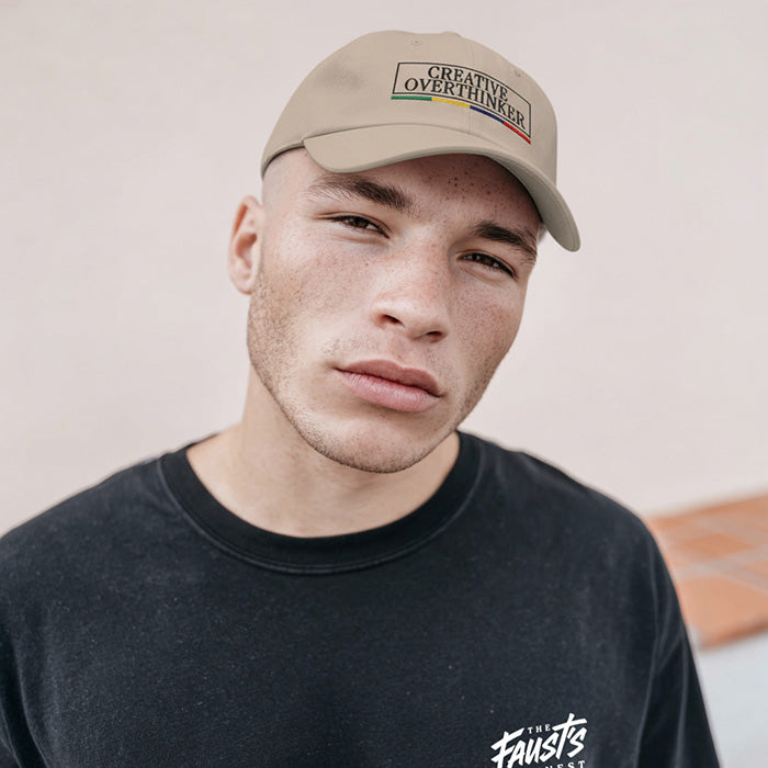 Man wearing a cap with 'Creative Overthinker' text and a black t-shirt with visible branding.