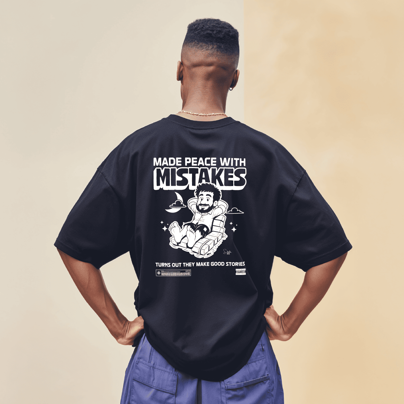 Person wearing a black t-shirt with a graphic and text on the back, standing against a beige background