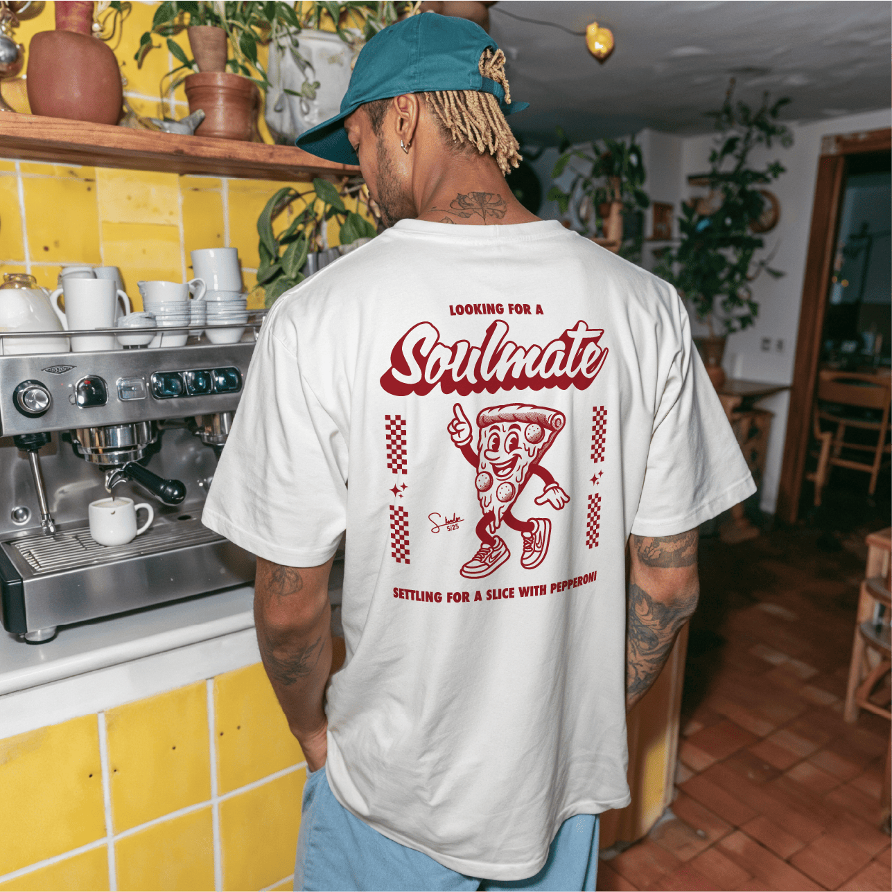 Person wearing a white t-shirt with a graphic design in a cafe setting