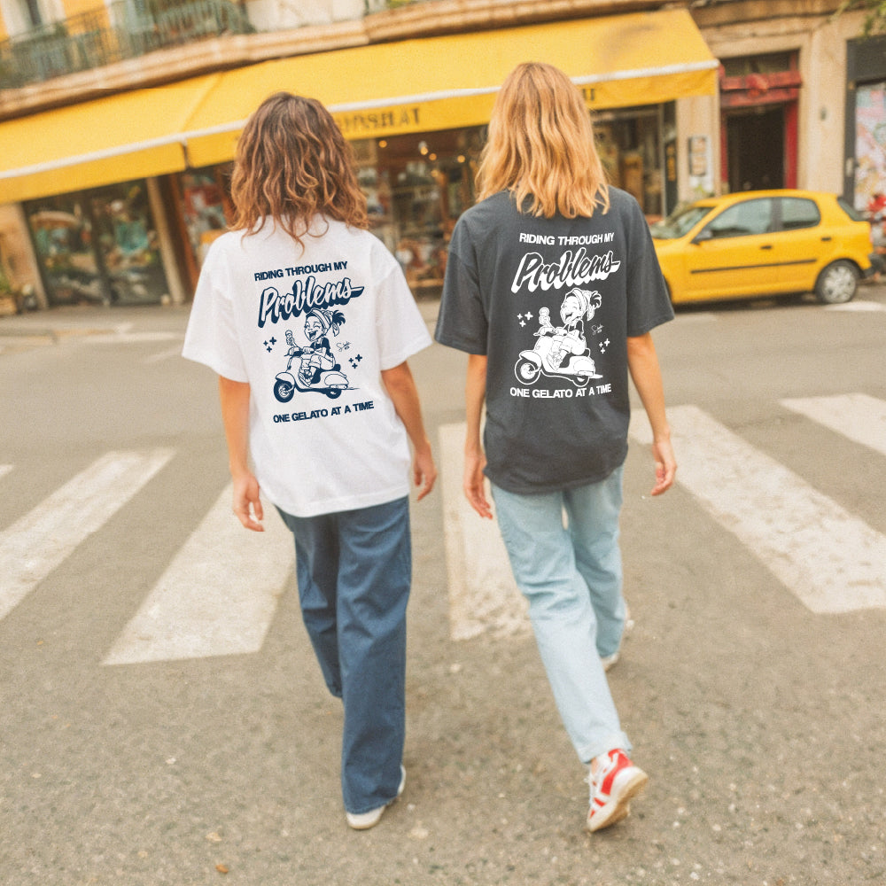 Two people walking on a street wearing t-shirts with a graphic design and text.