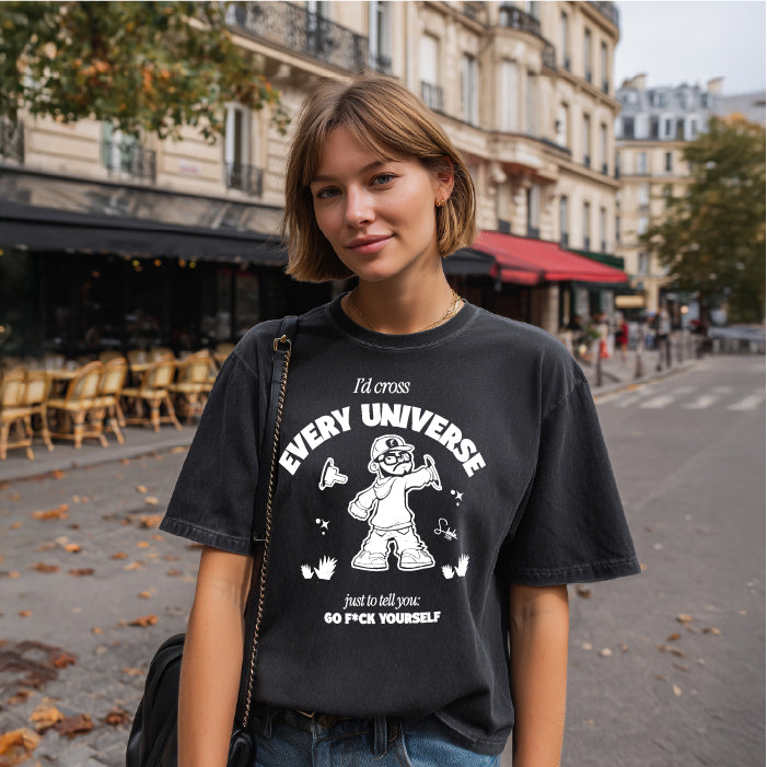 Person wearing a black t-shirt with graphic design and text on a city street.