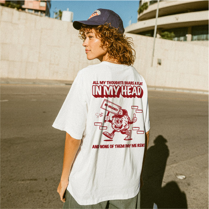 Person wearing a white t-shirt with red text and graphics on a street.