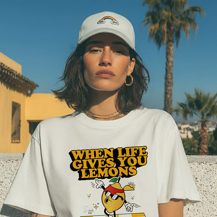Person wearing a white t-shirt with 'When Life Gives You Lemons' text and graphic, standing outdoors with palm trees in the background.