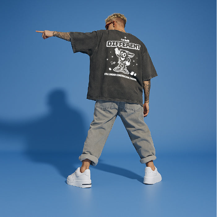 Person wearing a black oversized t-shirt with text and graphics on the back, standing against a blue background.