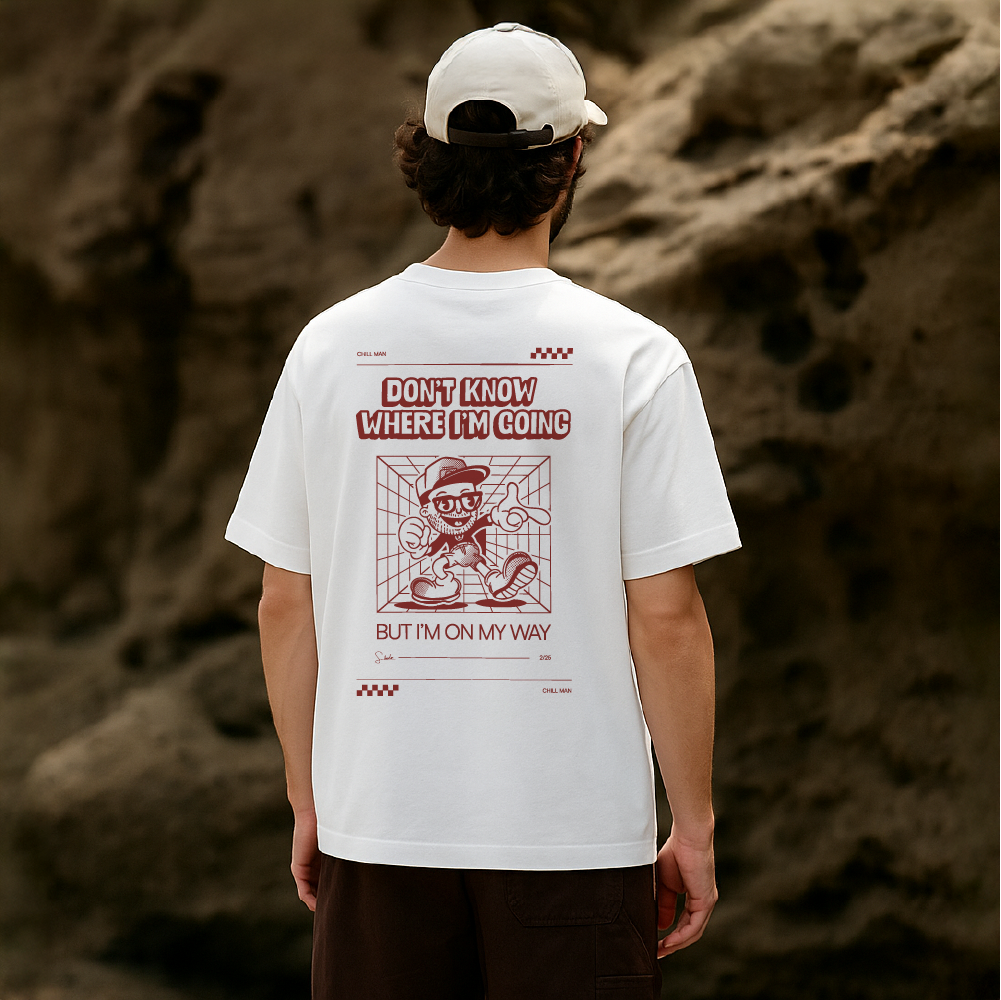 Person wearing a white t-shirt with a graphic design and text on the back, standing against a rocky background.