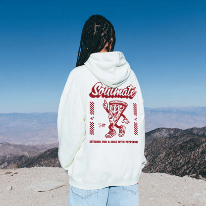 Person wearing a hoodie with a pizza graphic and text, standing on a mountain with a clear blue sky.