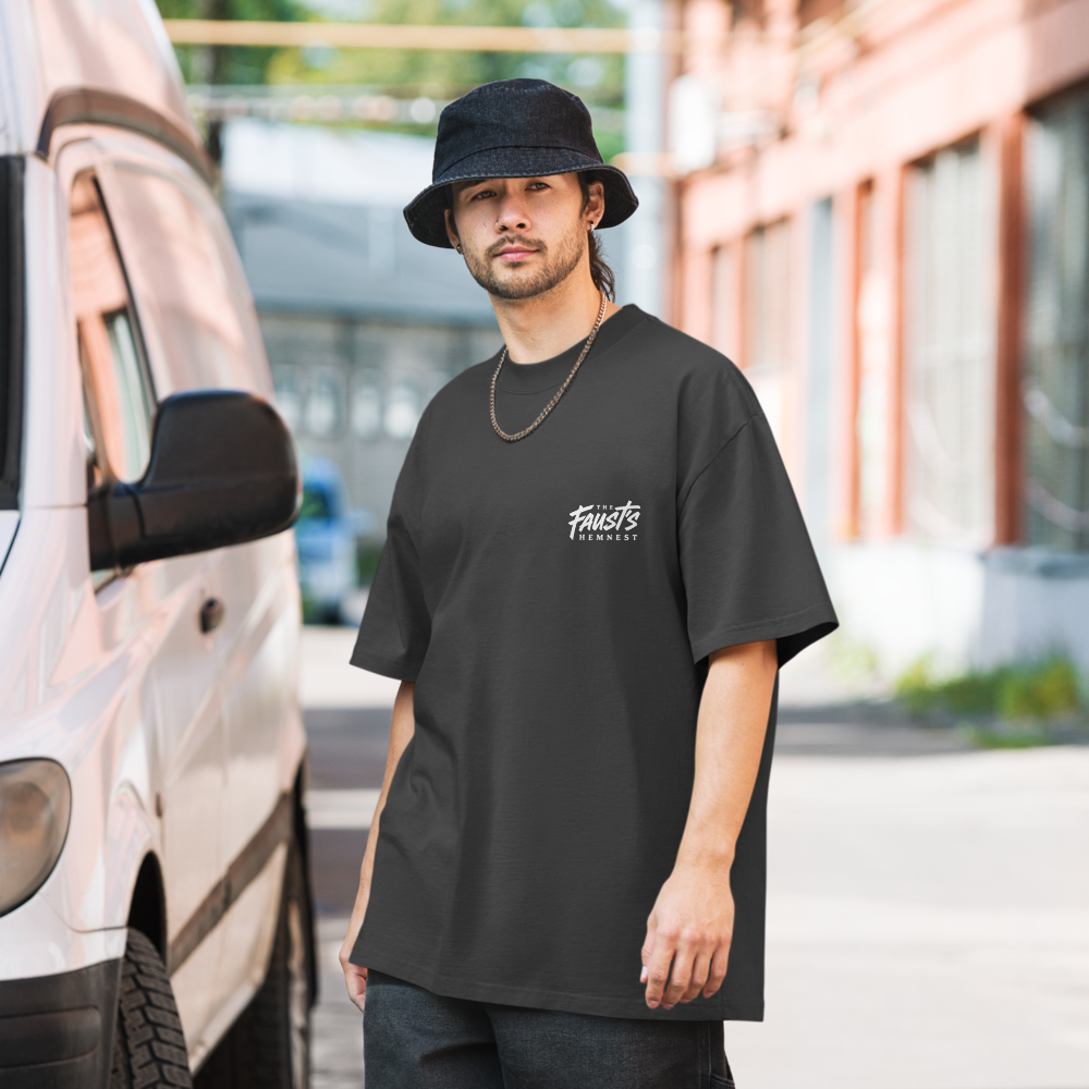 Man wearing a black t-shirt with a logo, standing outdoors near a vehicle.