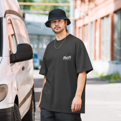 Man wearing a black t-shirt with a logo, standing outdoors near a vehicle.